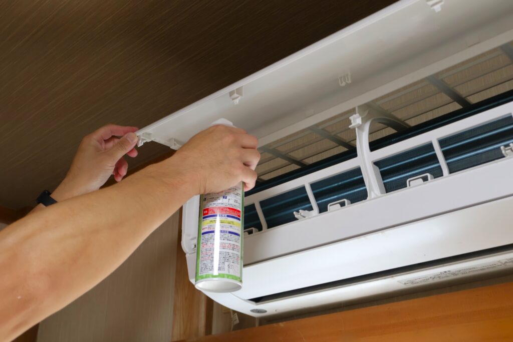 スプレーを使ってエアコン掃除をしている画像